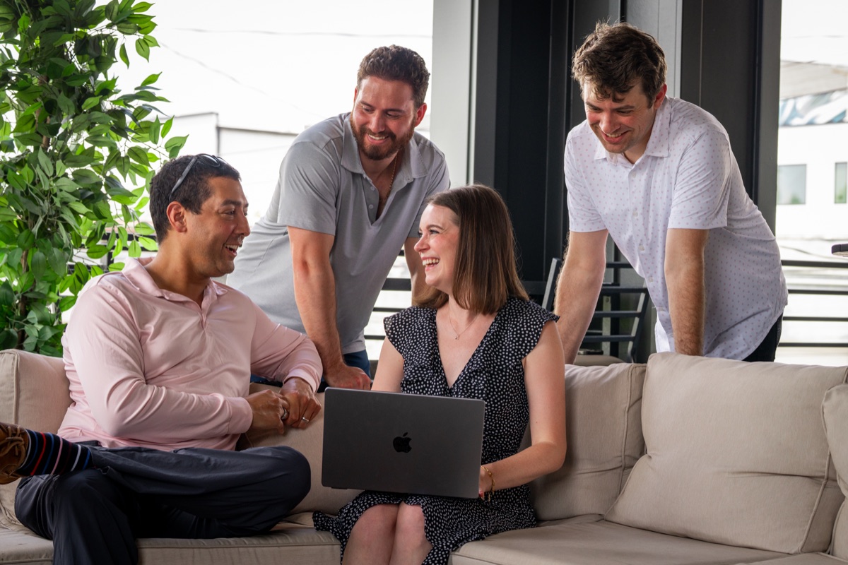 Three colleagues gathered around a laptop